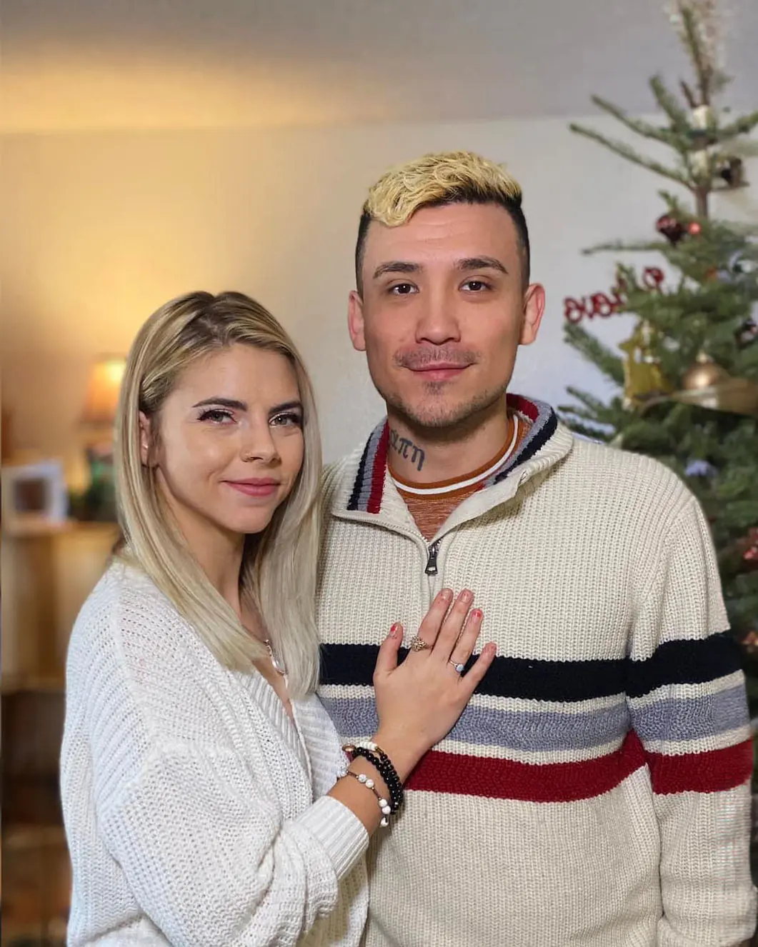 Anthony Polanco with his partner beside a Christmas tree.
